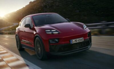 Red luxury SUV driving on a road at sunset.