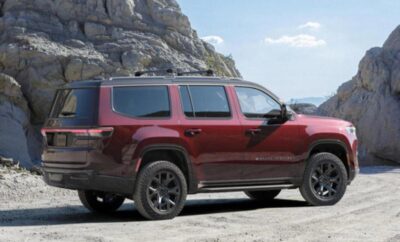 A red SUV parked on a rocky terrain near a mountain.