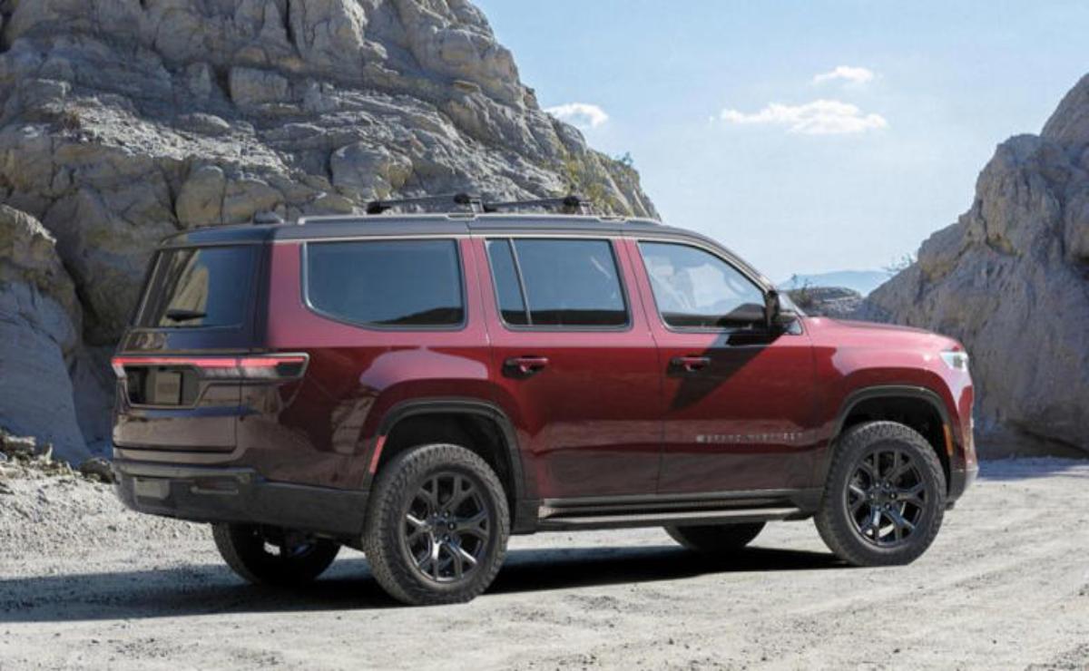 A red SUV parked on a rocky terrain near a mountain.