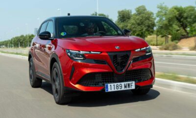 Red Alfa Romeo SUV driving on a sunny road.