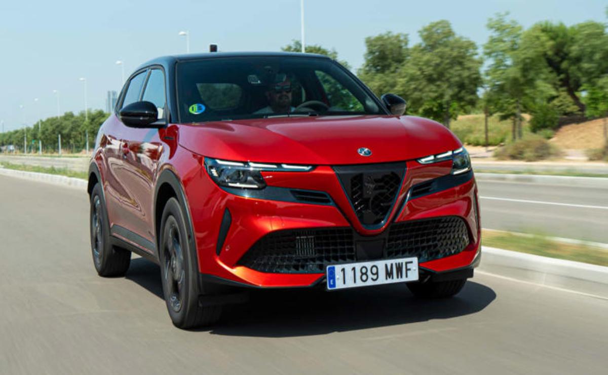 Red Alfa Romeo SUV driving on a sunny road.