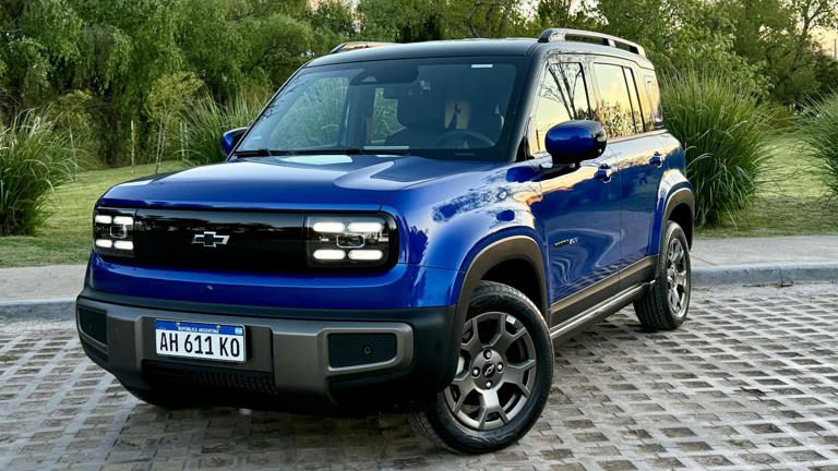 Blue modern SUV parked on a cobblestone driveway.