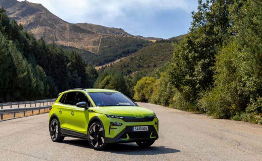 A man working on his laptop and writing in a notebook at a desk.