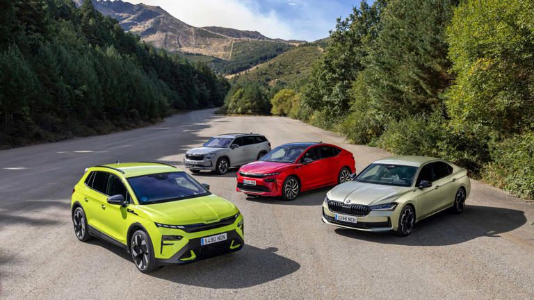 Four colorful cars parked on a winding mountain road surrounded by greenery.