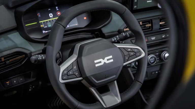 Close-up of a modern car steering wheel with controls and a digital dashboard.