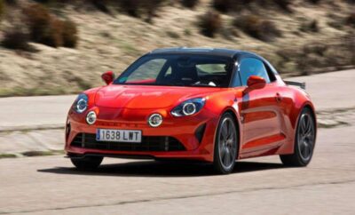 Red sports car driving on a winding road.