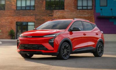Red modern electric SUV parked in front of a brick building.