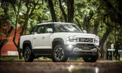White Ford Bronco parked on a forest path with trees in the background.