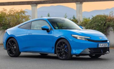 Sleek blue electric car parked outdoors with mountains in the background.
