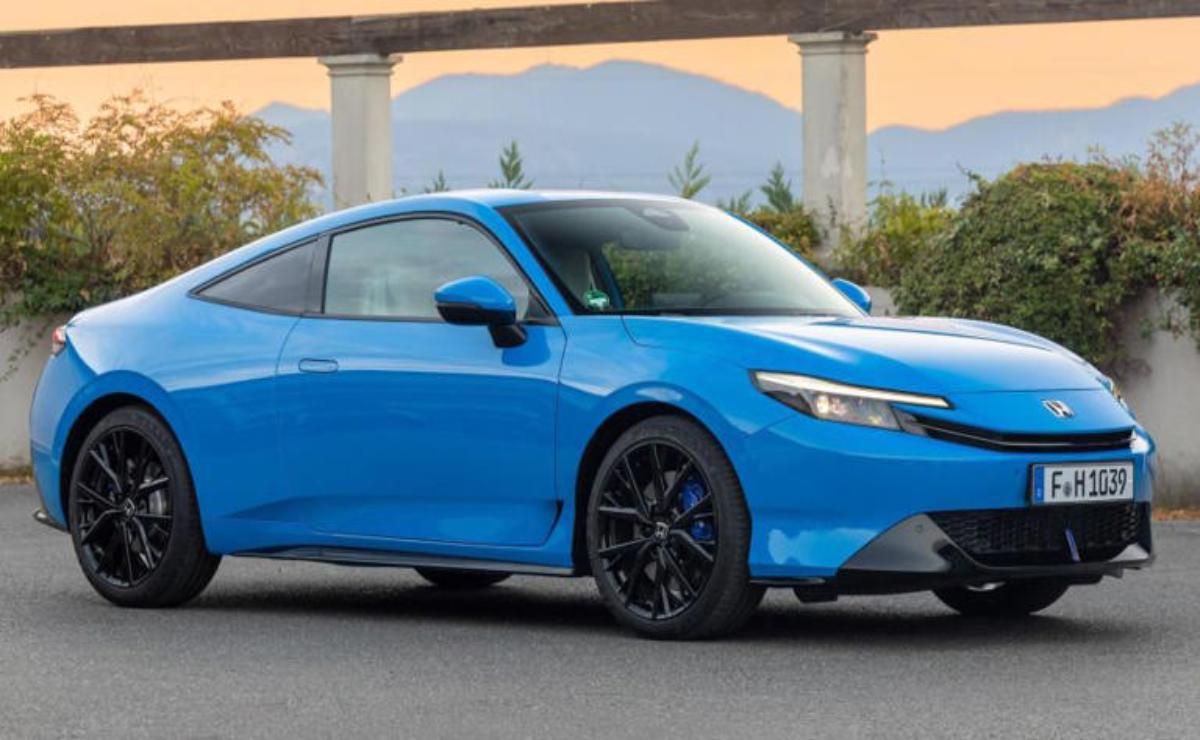 Sleek blue electric car parked outdoors with mountains in the background.