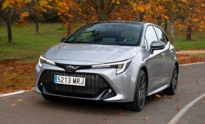 Silver Toyota Corolla parked on a road with autumn trees in the background.