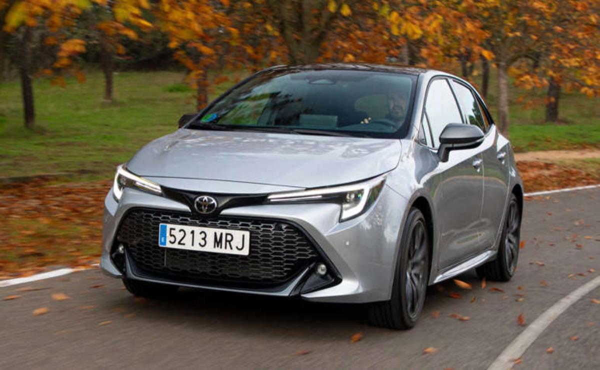 Silver Toyota Corolla parked on a road with autumn trees in the background.