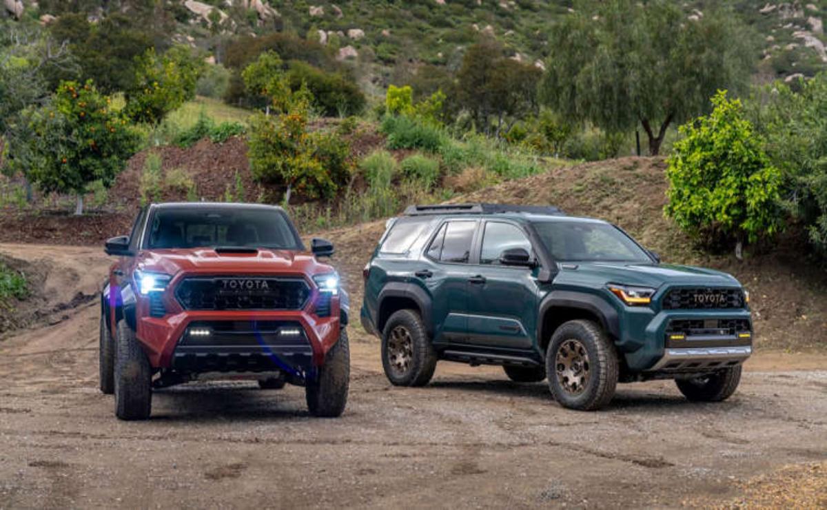 Two modern SUVs parked on a dirt path in a natural setting.