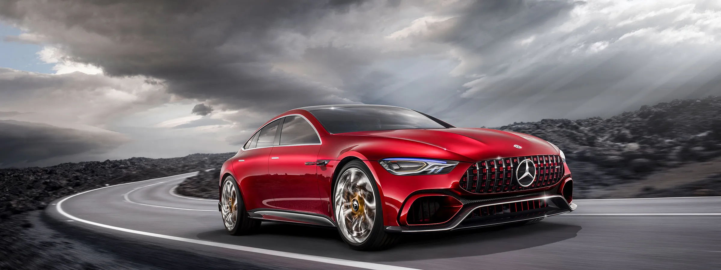 A sleek red sports car with dramatic lighting and cloudy sky.