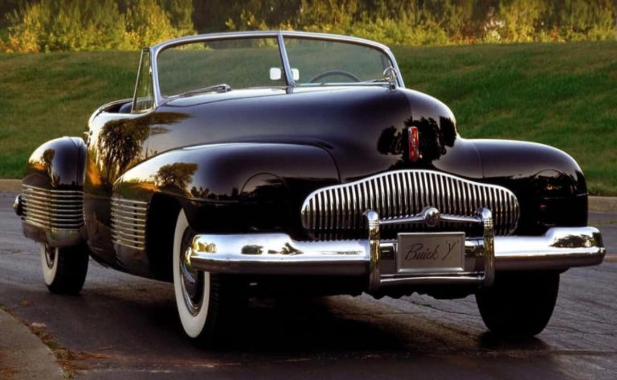 Classic black convertible car parked outdoors with sunlight reflecting on its shiny surface.
