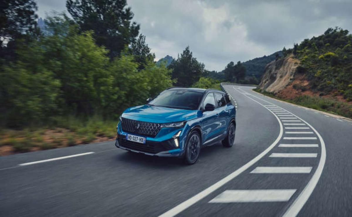 A blue SUV driving on a winding road surrounded by trees and hills.