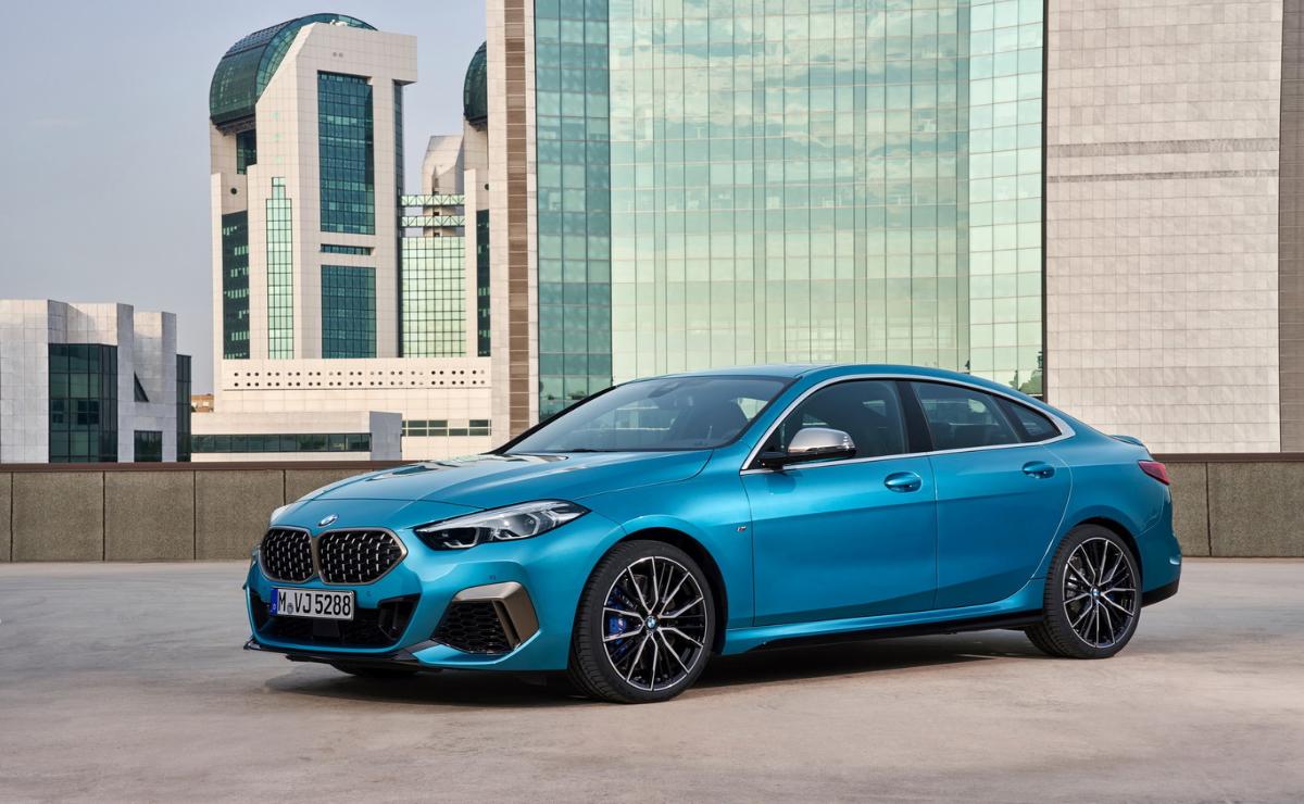 A sleek blue sports car parked in front of modern glass buildings.