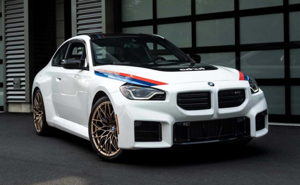 White BMW with sporty accents and bronze rims parked outside a building.