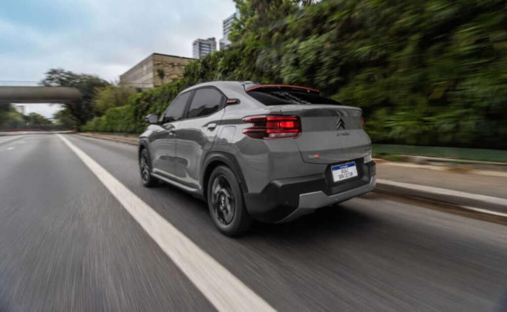 A man working on his laptop and writing in a notebook at a desk.