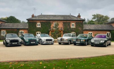 A lineup of classic cars parked in front of a rustic ivy-covered building.