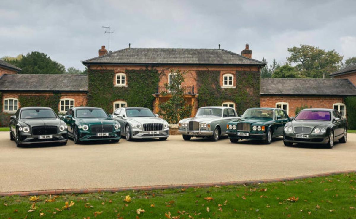 A lineup of classic cars parked in front of a rustic ivy-covered building.