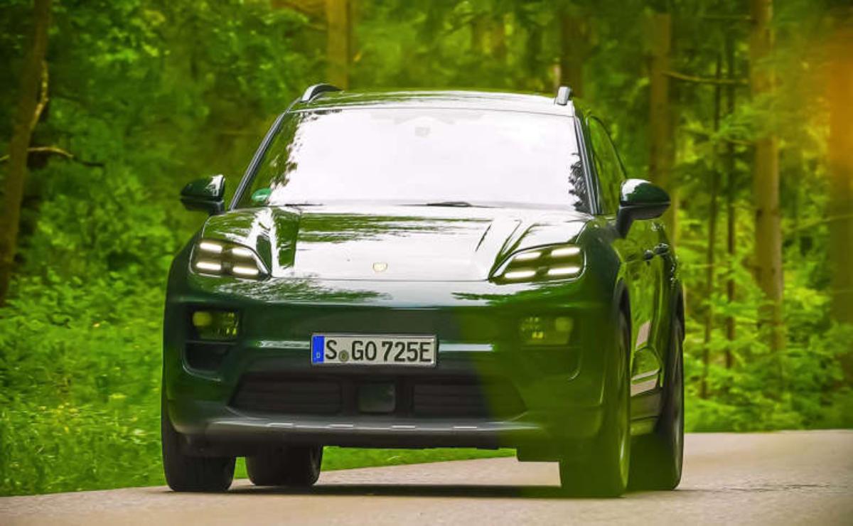 A sleek green sports car driving on a forest road.