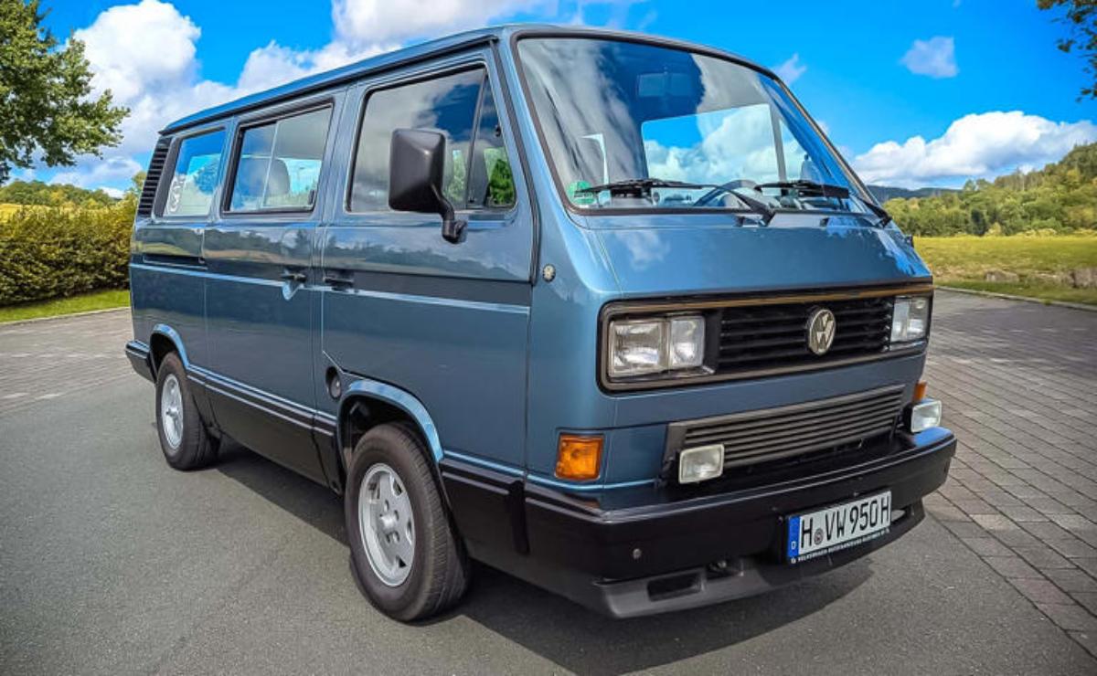A classic gray Volkswagen camper van parked under a blue sky.