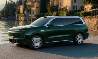 Sleek green SUV parked by a waterfront with historic buildings.