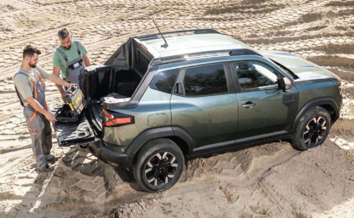 A green SUV stuck in the sand with a man trying to free it.