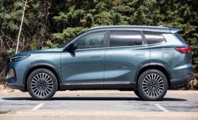 A sleek blue SUV parked with a forest backdrop.