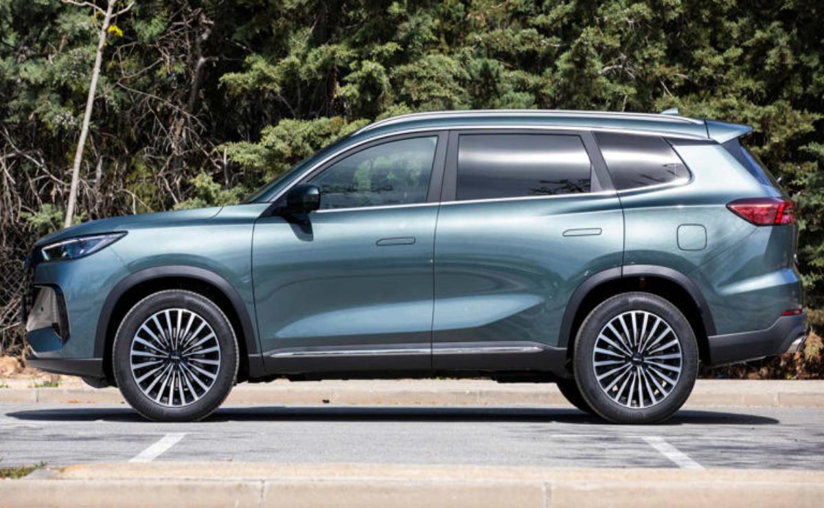 A sleek blue SUV parked with a forest backdrop.