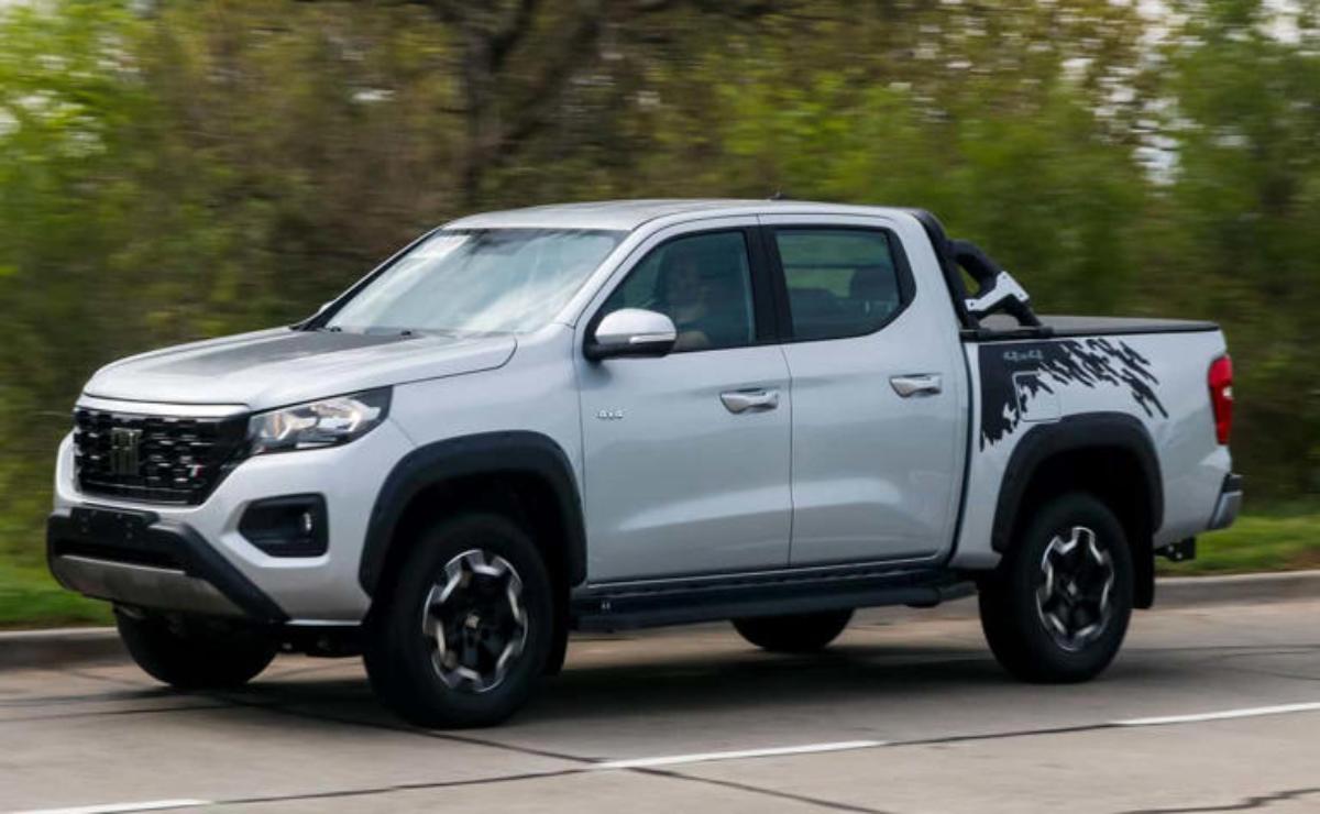 A white pickup truck driving on a road with greenery in the background.
