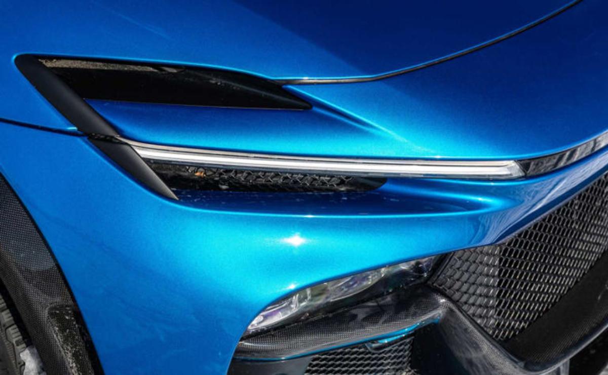 Close-up of a sleek blue car's futuristic headlight and grille design.