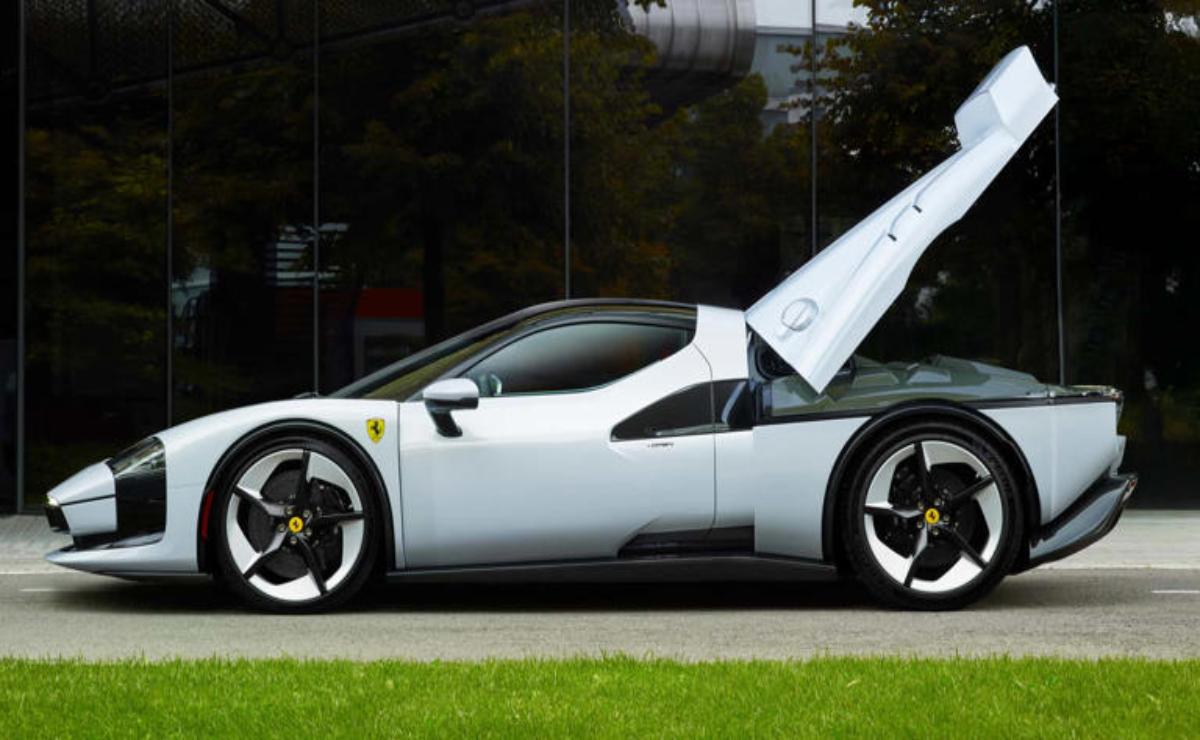 White sports car with open gull-wing door parked on grass.