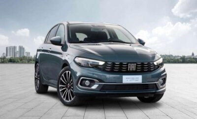 A modern blue Fiat Tipo hatchback parked on a tiled surface under a cloudy sky.