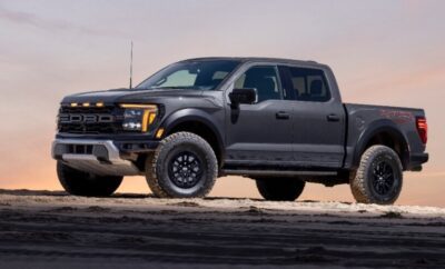 Black Ford pickup truck parked on rough terrain under clear sky.