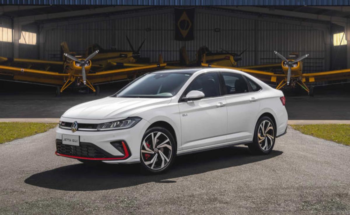 A white sporty hatchback parked outdoors near industrial equipment.