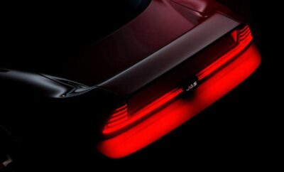 Close-up of a car's rear red taillight glowing in the dark.