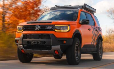Orange Honda SUV driving on a road with autumn trees in the background.