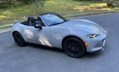Silver convertible sports car parked on a residential street.