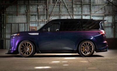 A dark blue customized car with large bronze rims parked indoors.