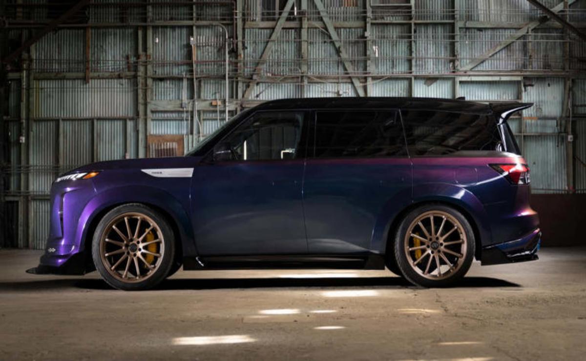 A dark blue customized car with large bronze rims parked indoors.