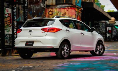 White Nissan hatchback parked on a colorful city street.