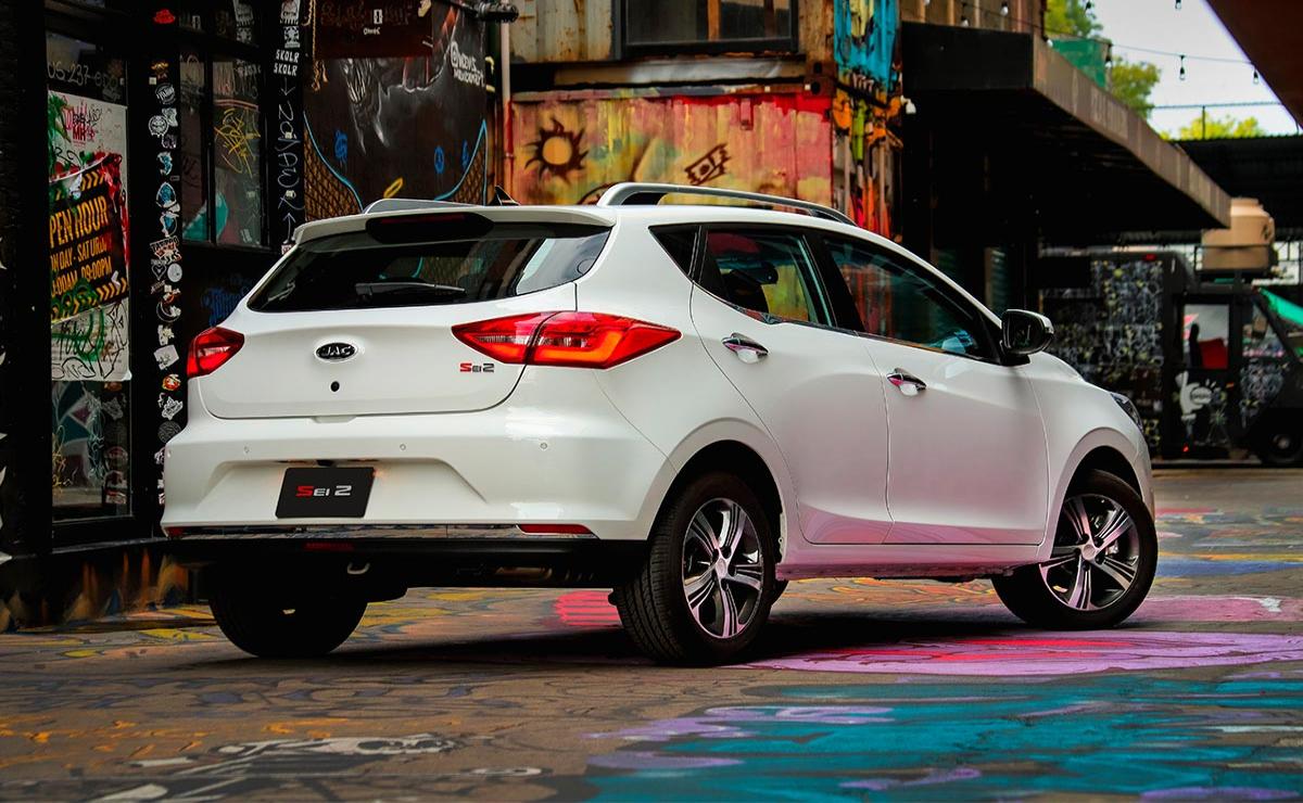White Nissan hatchback parked on a colorful city street.