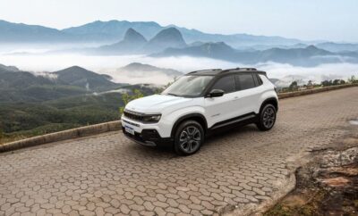 White SUV parked on a scenic mountain road with misty peaks in the background.