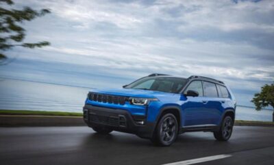 Blue SUV driving on a coastal road under a cloudy sky.