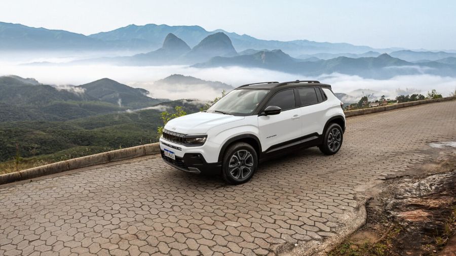 White SUV parked on a scenic mountain road with misty peaks in the background.