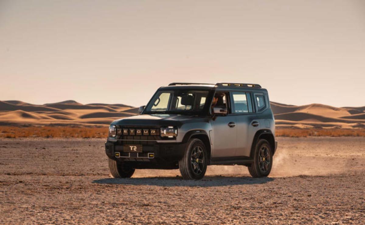 A rugged SUV parked on a desert landscape at sunset.