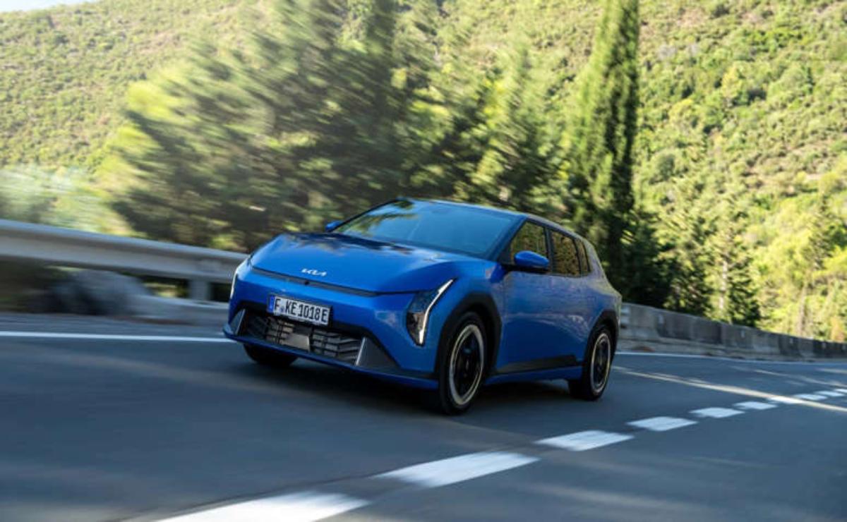 Blue electric car driving on a scenic road surrounded by trees.