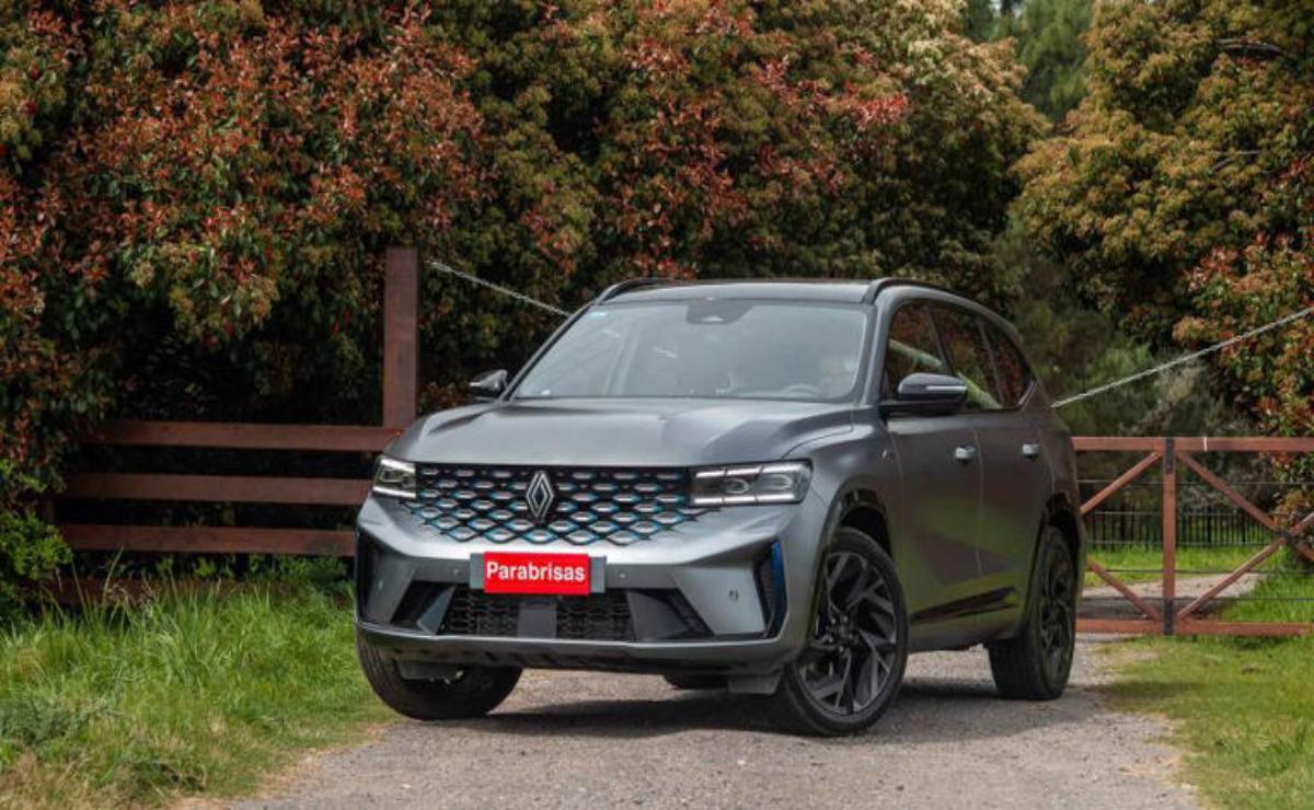 A modern gray SUV parked on a path with autumn foliage in the background.